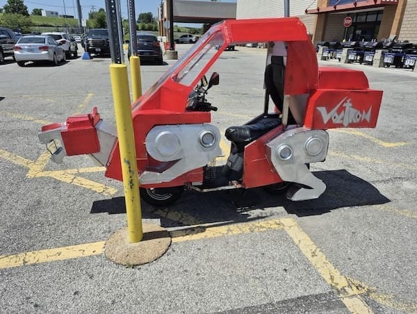 Photo of a DIY red Voltron vehicle parked outside, made to look like the classic robot lion.