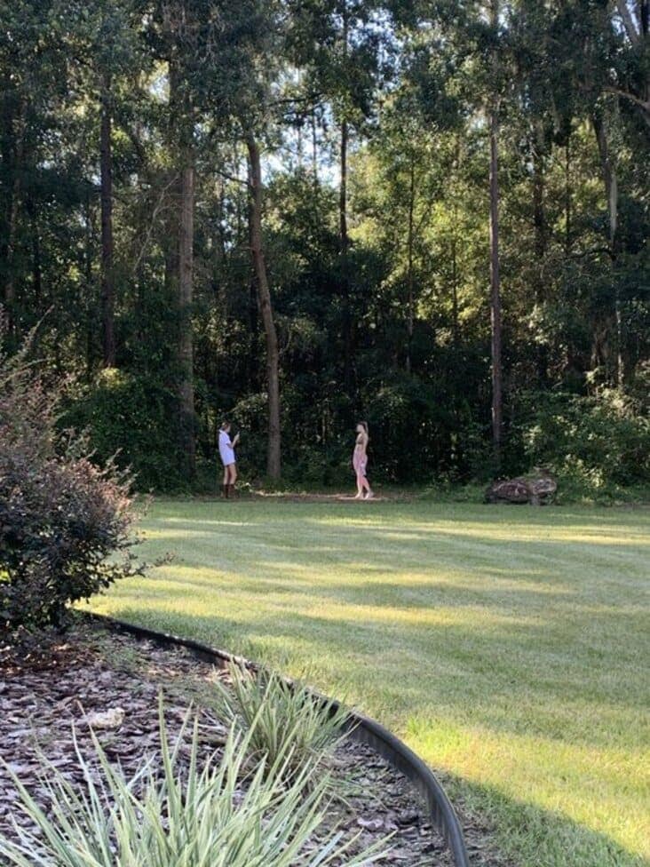The behind-the-scenes shot of the influencer's photoshoot, revealing she's just posing in a regular backyard.