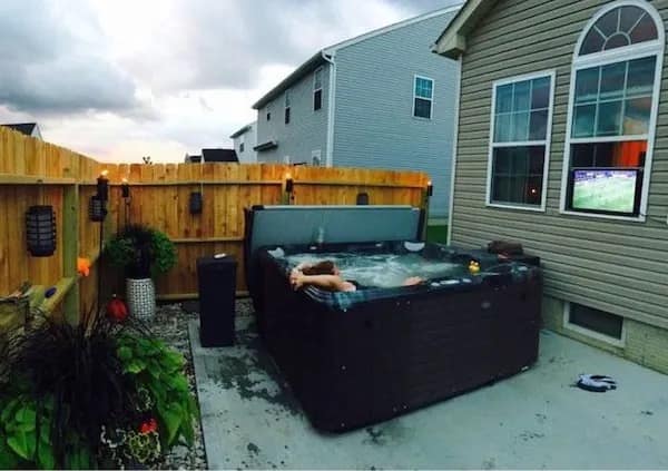 Backyard hot tub with outdoor TV mounted on house