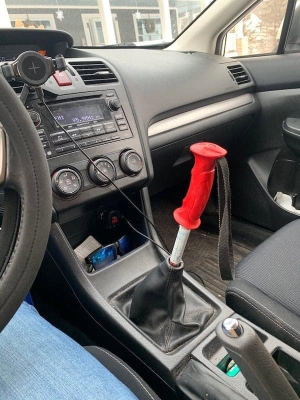 A car's gear shift knob replaced with a red ski pole handle in a great redneck engineering fix.