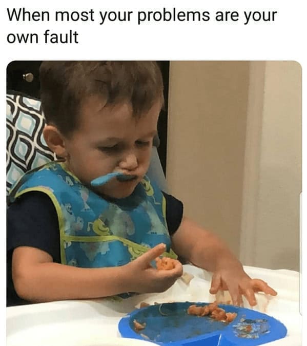 A toddler frowning at a messy plate, looking frustrated.