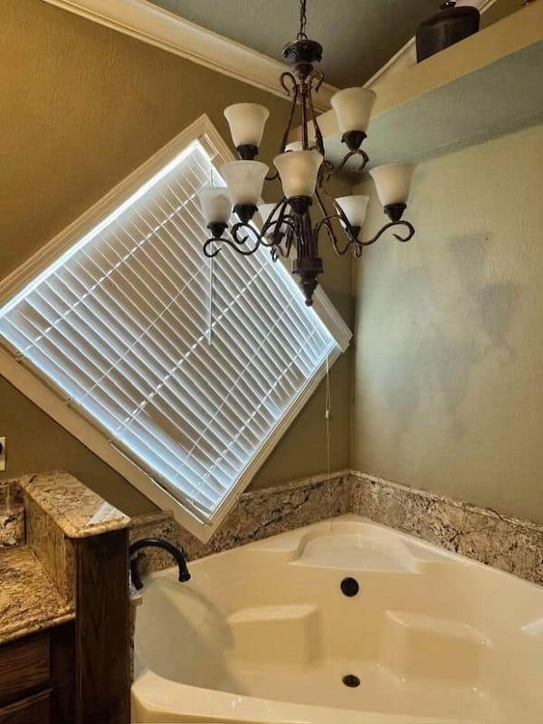 A construction fail in a bathroom with a large diagonal window right over the bathtub.