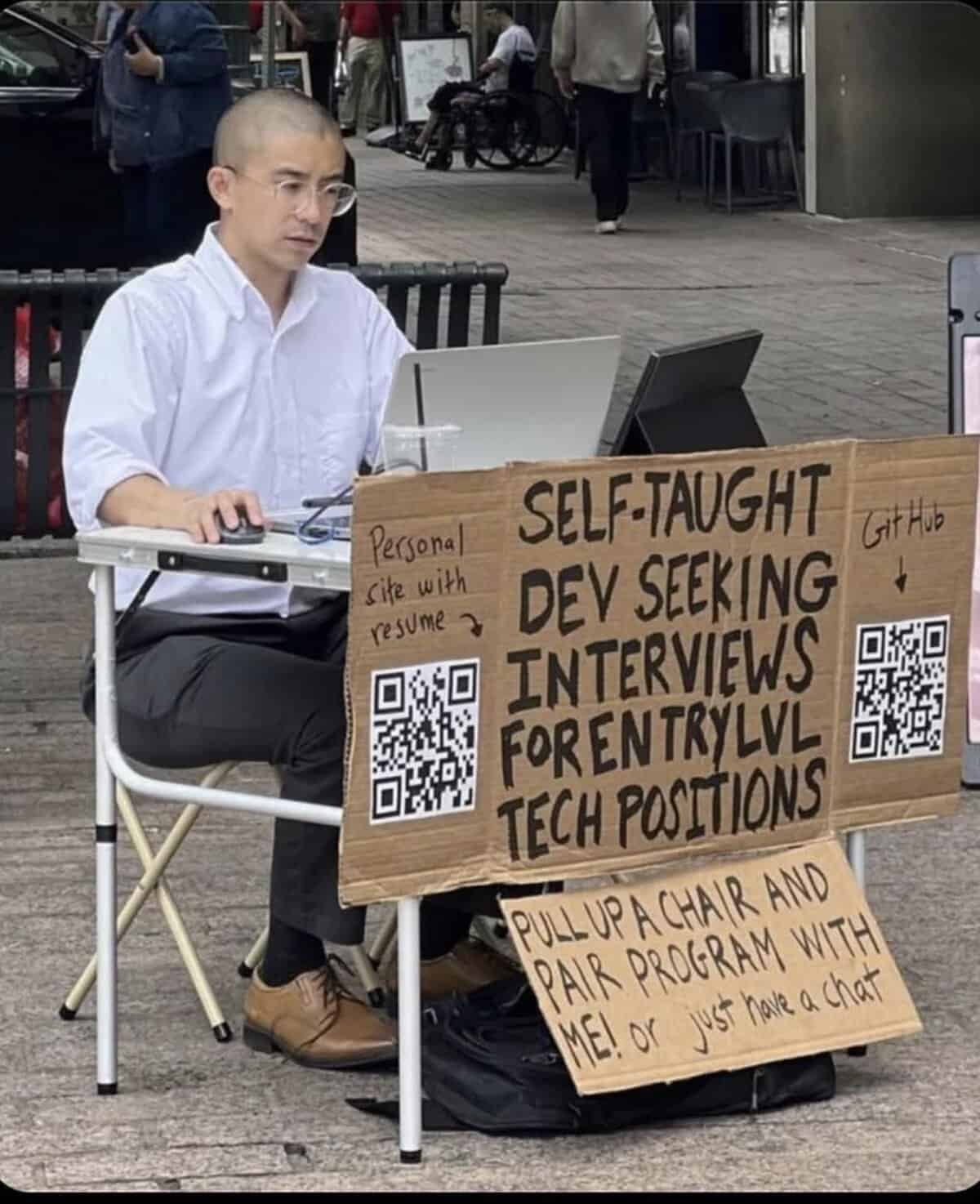 An inspiring programmer meme of a self-taught developer setting up a desk on the street to find a job