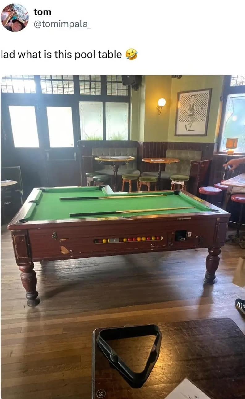 A classic meme photo of a bizarre L-shaped pool table in a pub.