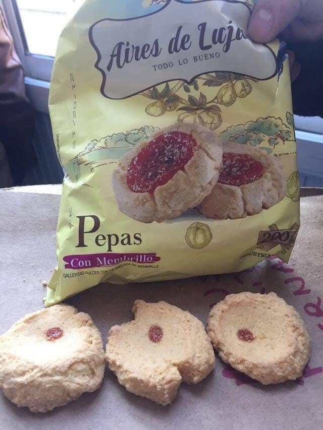 A bag of cookies showing large jam centers contrasted with the actual cookies having tiny red dots.