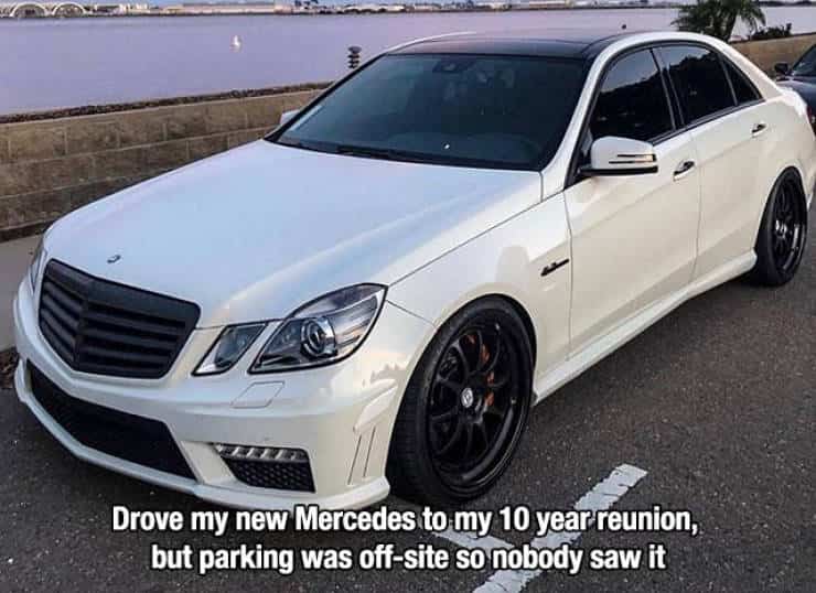 White Mercedes Benz parked on asphalt with a caption about a high school reunion.