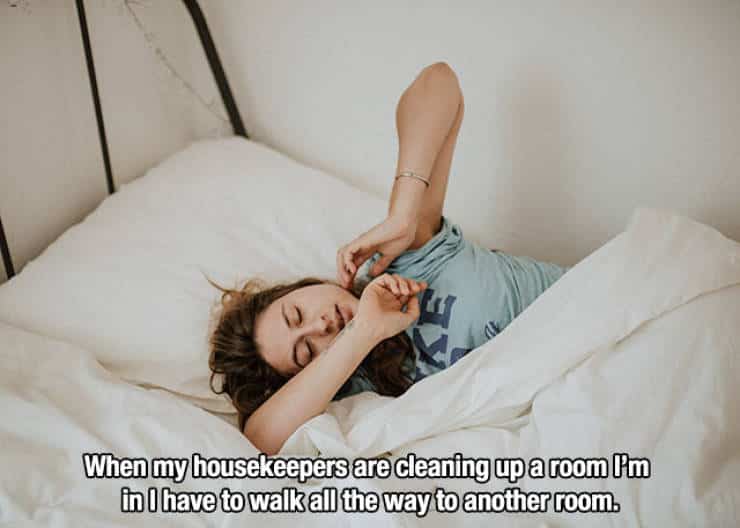 Woman lying in bed covering her eyes with a caption about housekeepers cleaning.