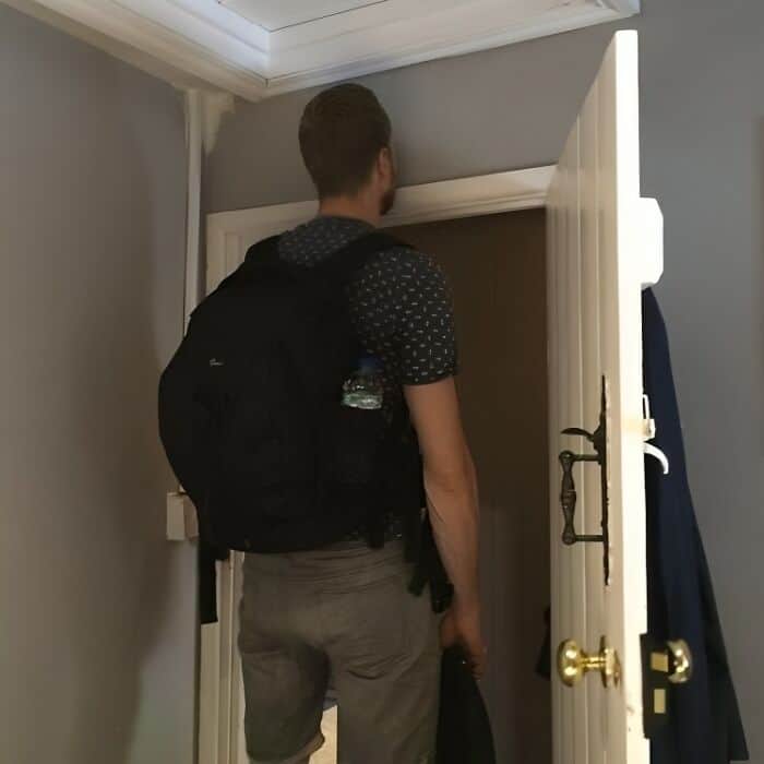 A tall people problems picture of a man whose head is higher than the door frame he is trying to walk through.