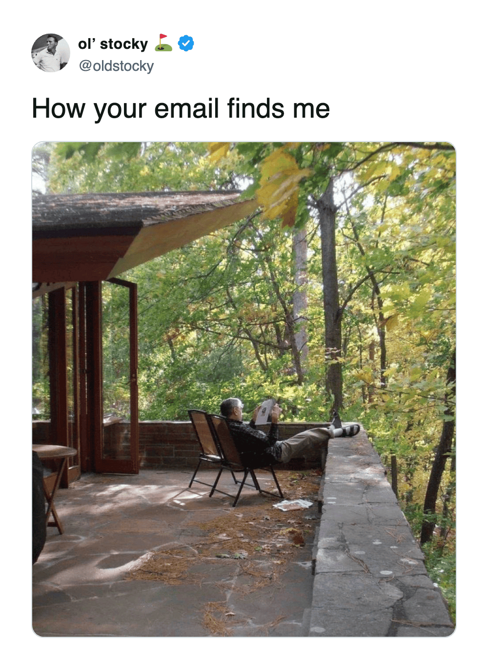Man relaxing on nature balcony reading paper ignoring work emails.
