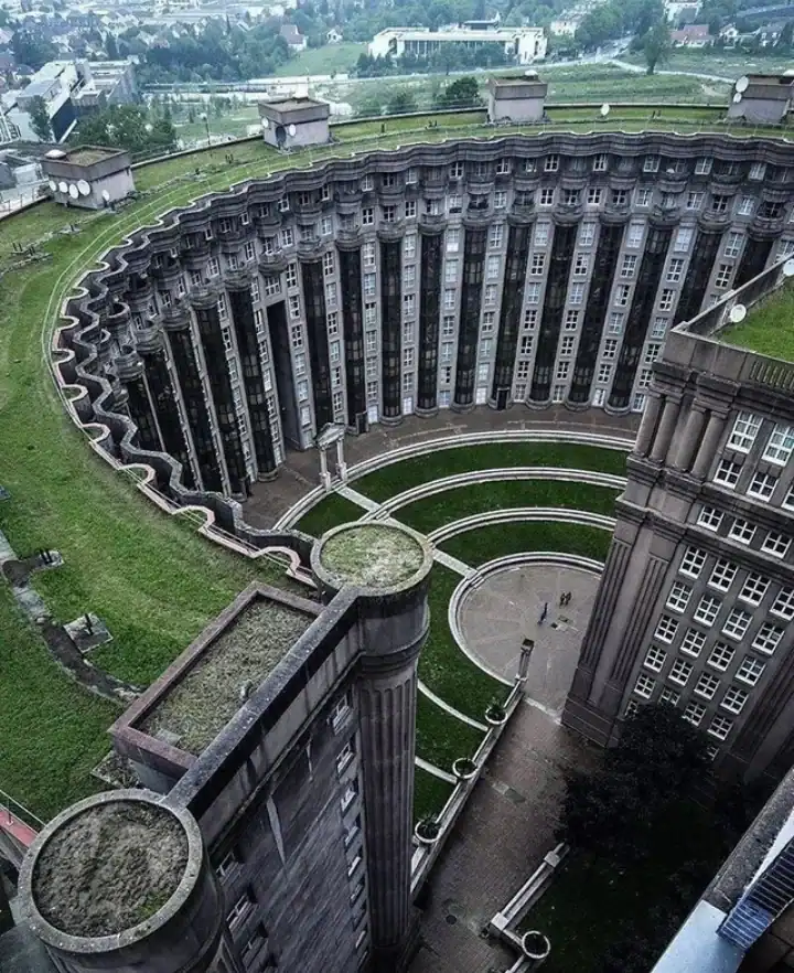 Massive circular Brutalist apartment complex in France with neoclassical columns and a sunken courtyard.
