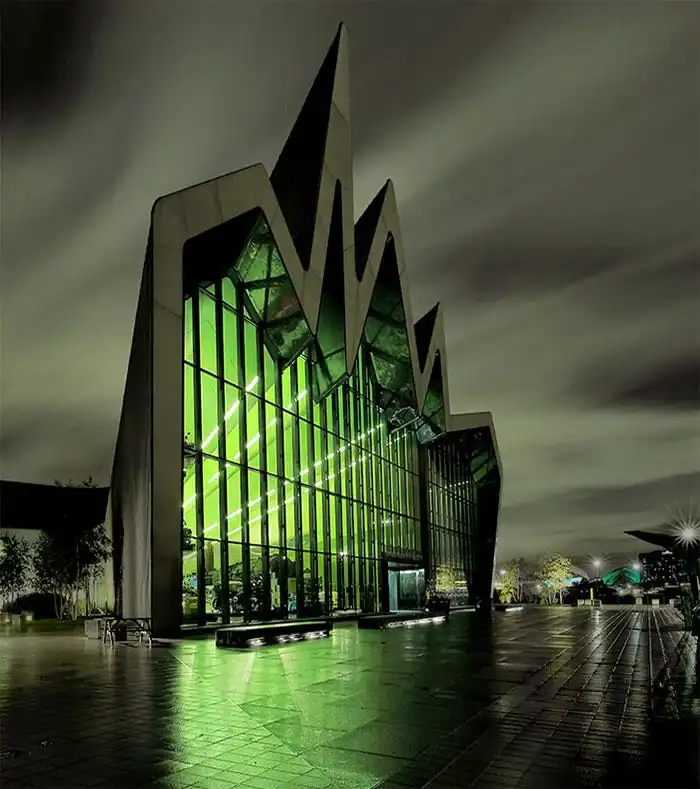 Riverside Museum in Glasgow at night featuring sharp jagged rooflines and eerie green interior lighting.
