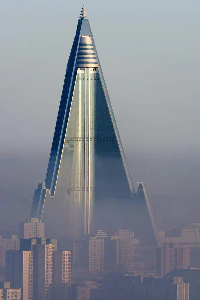 The towering Ryugyong Hotel in Pyongyang looms over the city skyline in a hazy fog.