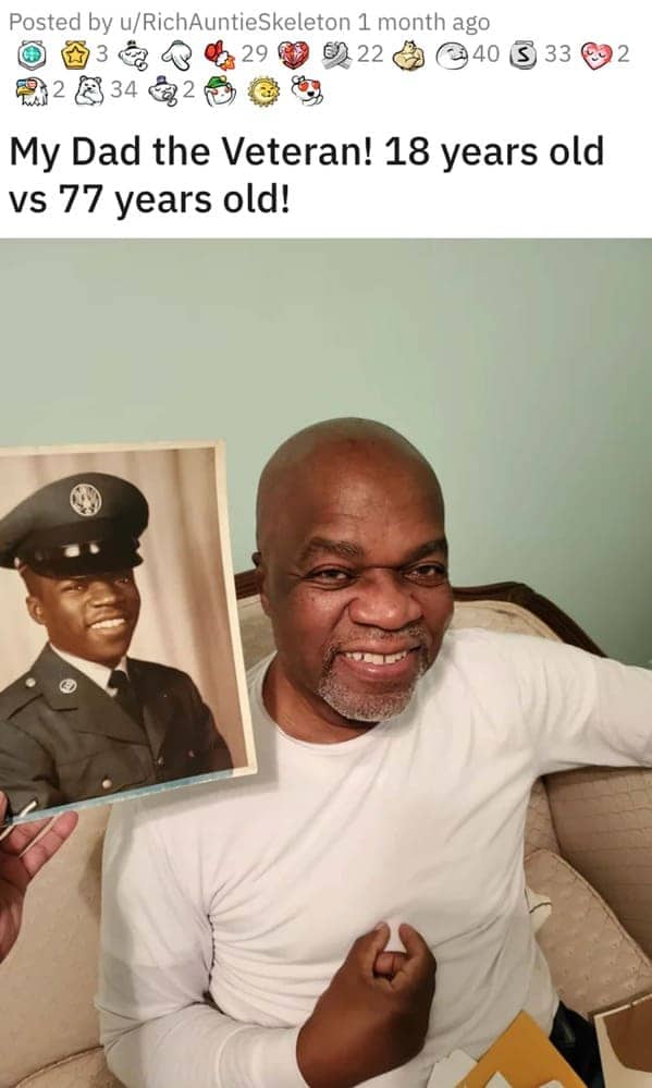 Veteran at age 77 holding a framed photograph of himself in uniform at age 18.
