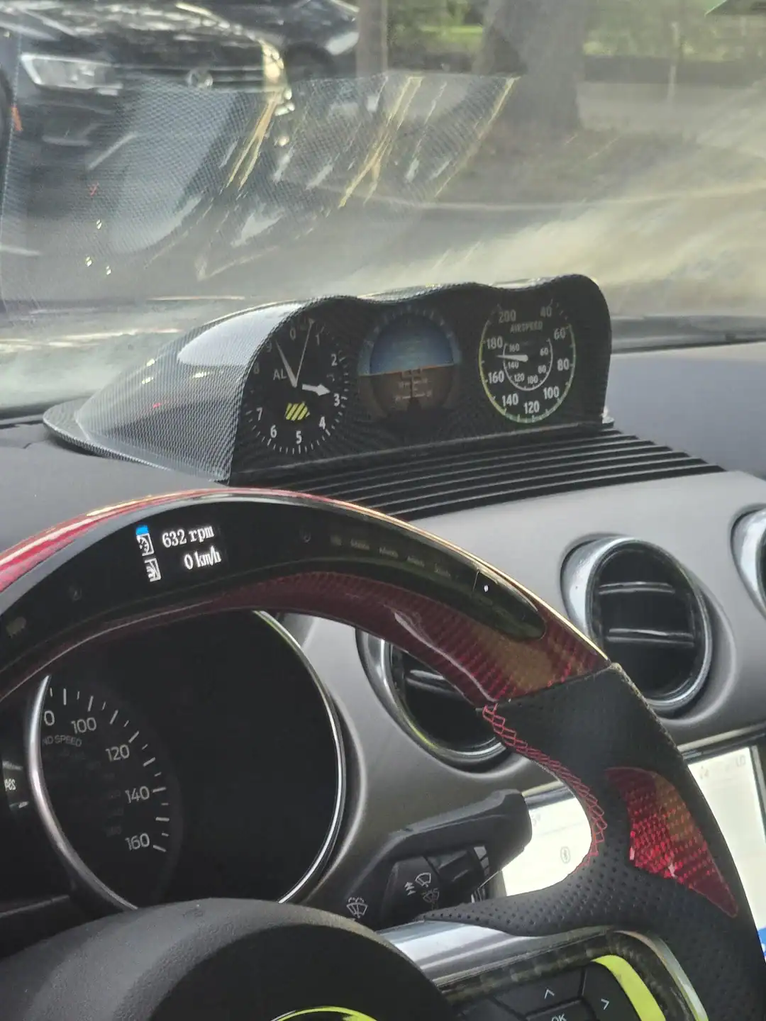 Car interior featuring aviation-style gauges and an altimeter mounted on the dashboard and steering wheel.