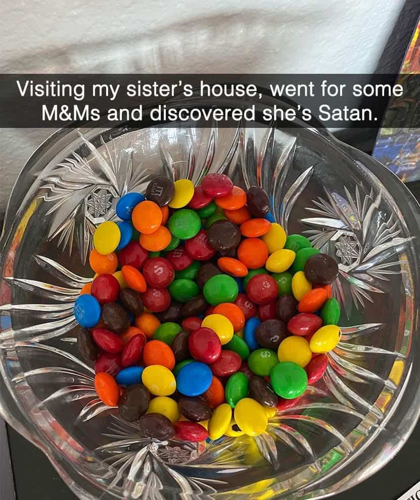 A crystal bowl filled with a chaotic mix of M&Ms and Skittles candies.