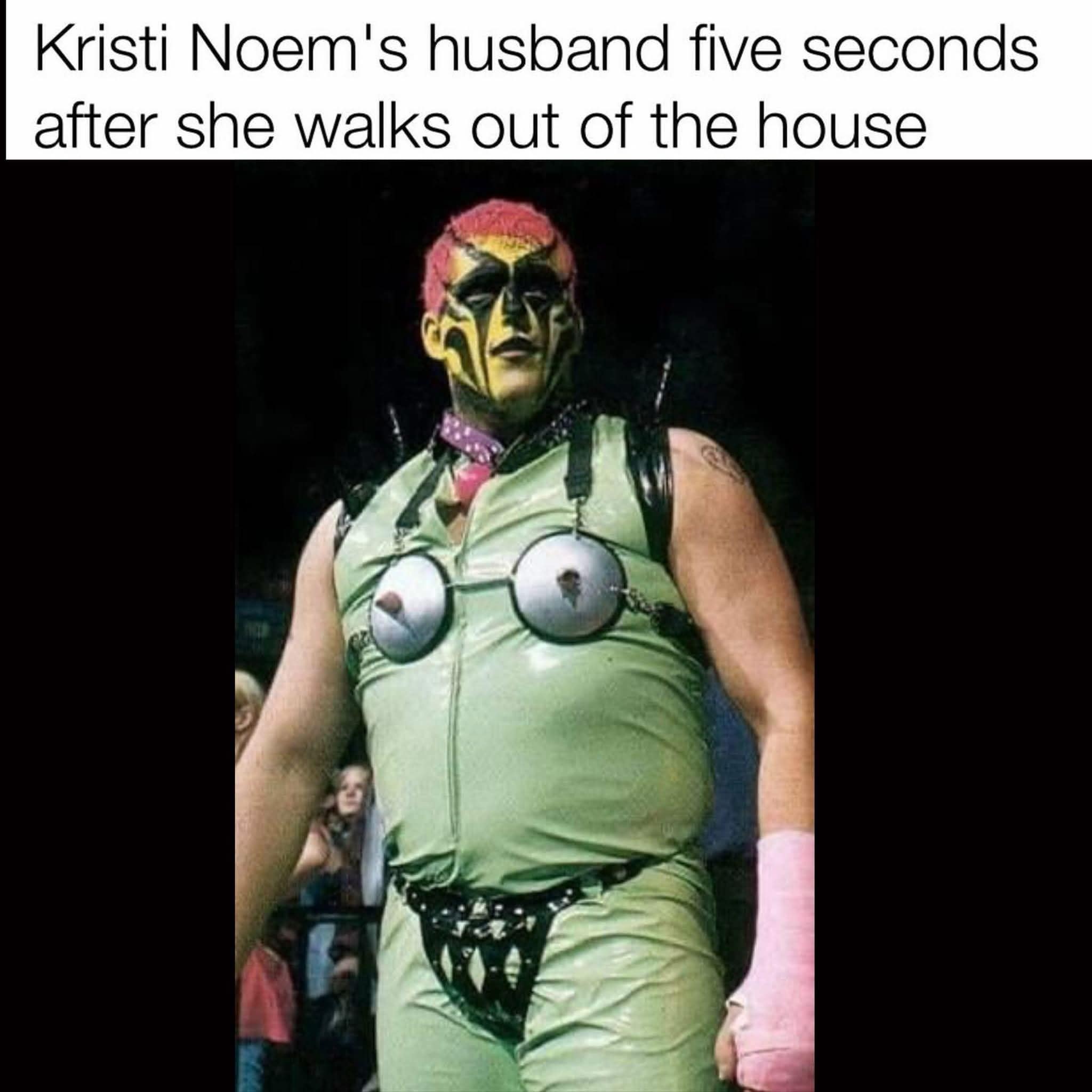 A political funny meme featuring the pro wrestler Goldust in an elaborate, bizarre green outfit and face paint. The text jokes this is "Kristi Noem's husband" as soon as she leaves the house, poking fun at recent political controversies.