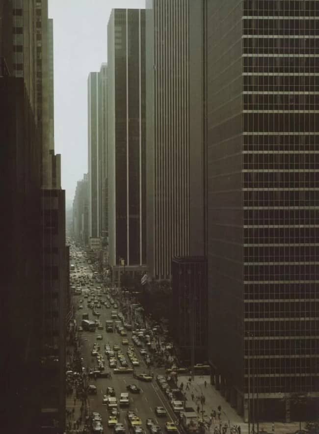 Vintage view down smoggy canyon of brutalist glass skyscrapers clogged with bumper-to-bumper traffic below