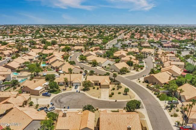 Aerial drone view of endless identical beige stucco suburban houses stretching to Arizona horizon
