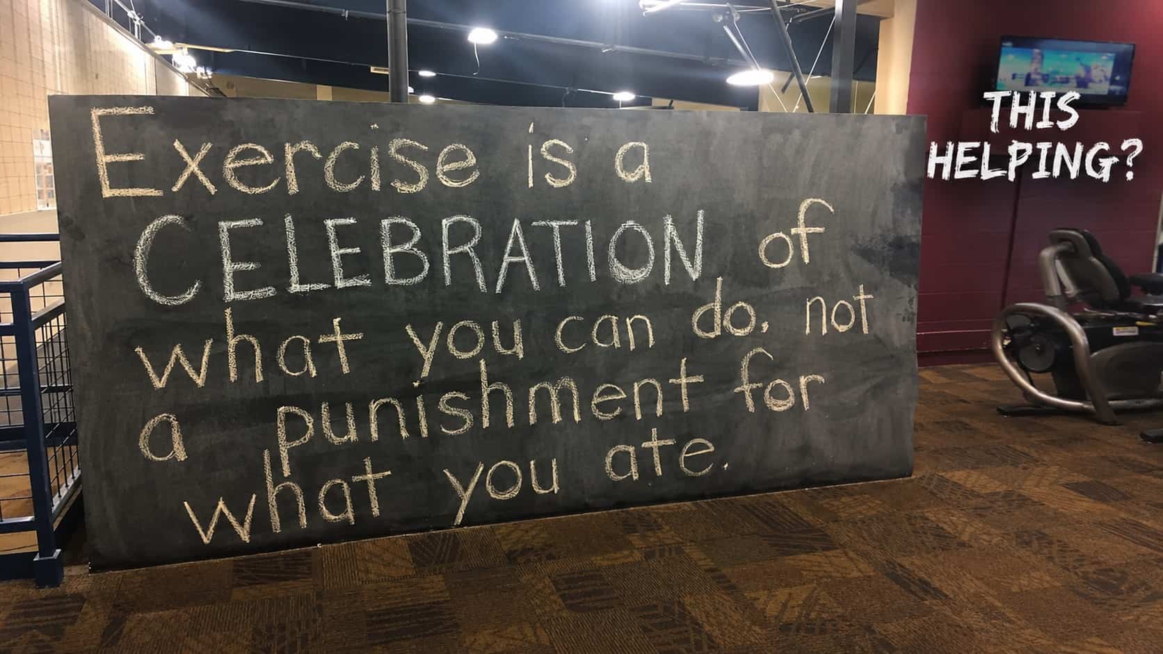 Chalkboard motivational message about exercise being a celebration not punishment inside a fitness gym.
