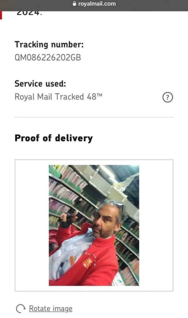 Postal worker delivery proof selfie inside a mail room facility instead of package drop location.