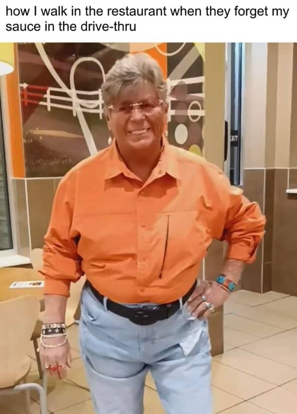 Confident person in an orange shirt posing in a fast food restaurant over missing drive-thru sauce
