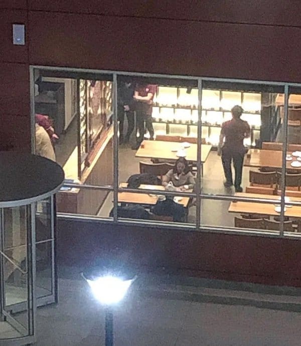 Restaurant staff standing around at closing time while one customer keeps eating at a table.