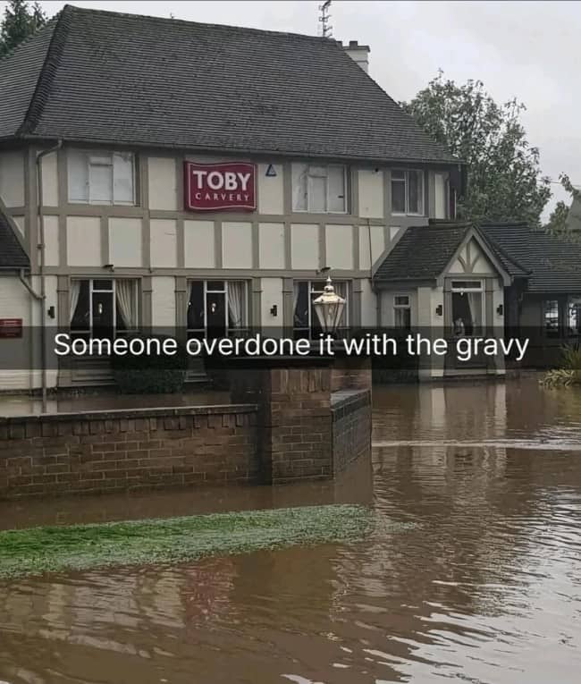 Flooded Toby Carvery pub surrounded by brown water, captioned someone overdone it with the gravy