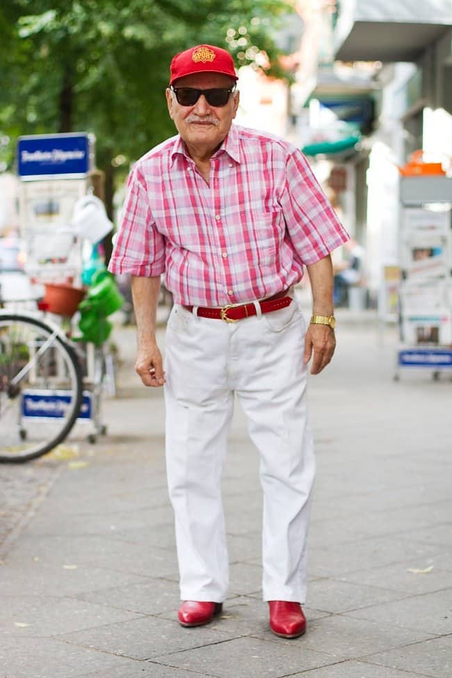 Stylish grandpa in a red cap, pink plaid shirt, white jeans, and matching red shoes