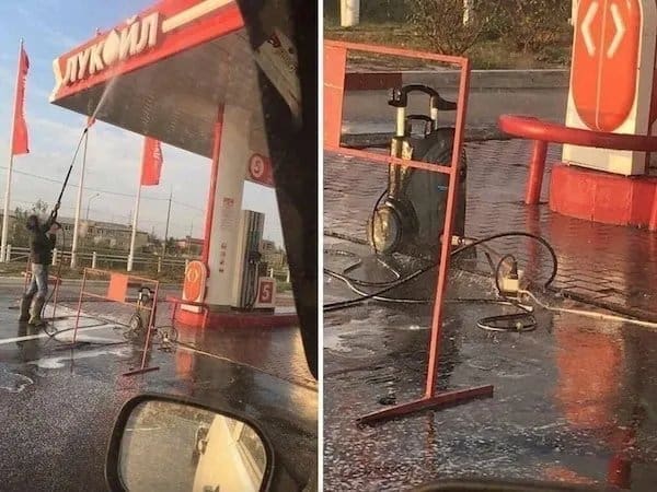 Worker pressure washing a gas station while the electric washer sits in a spreading puddle.