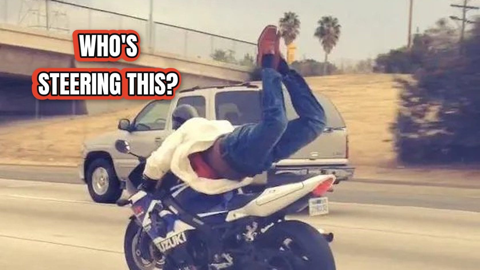 Motorcycle rider lying on his back with feet up on a freeway, the kind of stunt that makes Darwin Award winners.