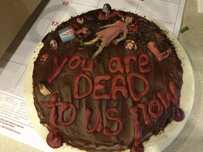 Chocolate cake with zombie figurines and red icing saying you are dead to us now