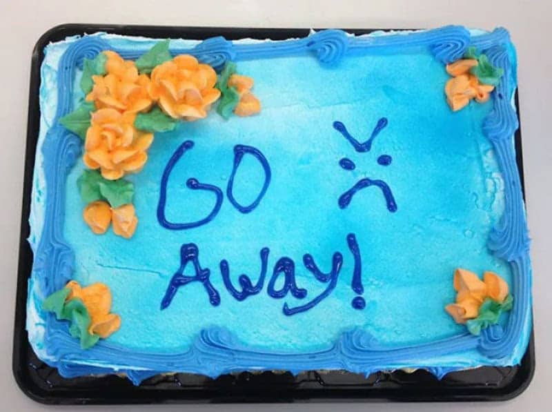 Blue sheet cake with orange roses and an angry face saying go away