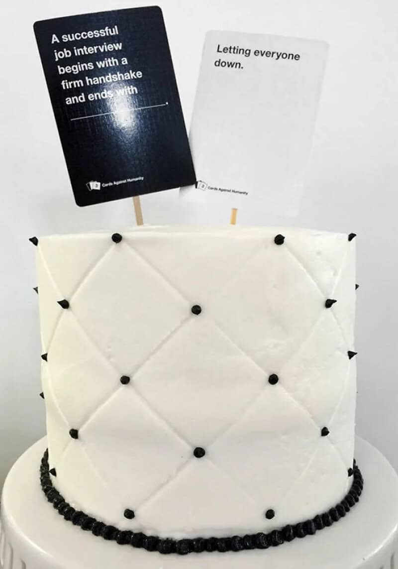 Quilted white cake topped with party game cards about job interviews and letting everyone down