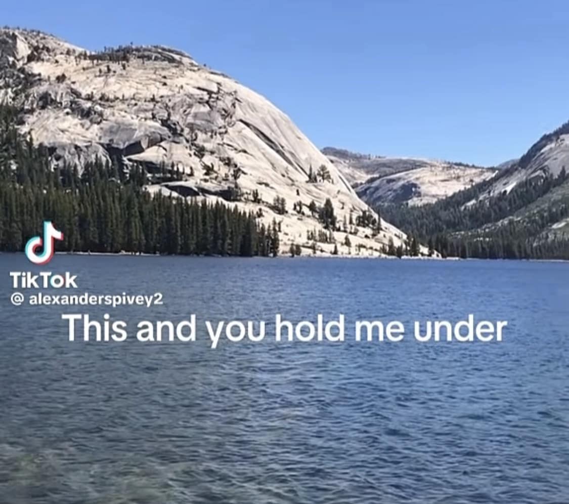 Gorgeous alpine mountain lake landscape overlaid with dark romantic text about being held underwater in a funny meme.