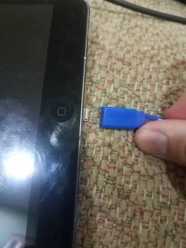 Blue USB connector pulled away while its metal tip stays stuck inside a tablet port