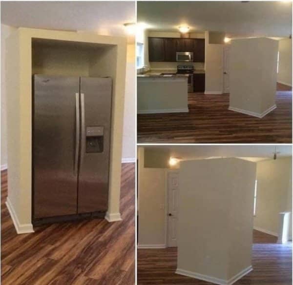 Refrigerator boxed into a freestanding wall enclosure in the middle of an open floor plan