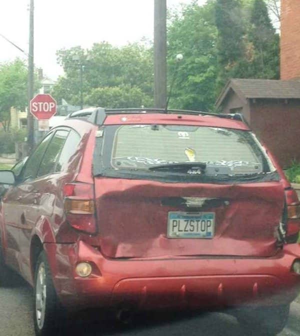 Badly dented red car with a license plate that reads PLZSTOP