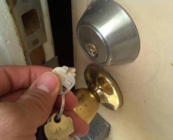 Hand holding a key snapped in half, the other half stuck inside a deadbolt lock