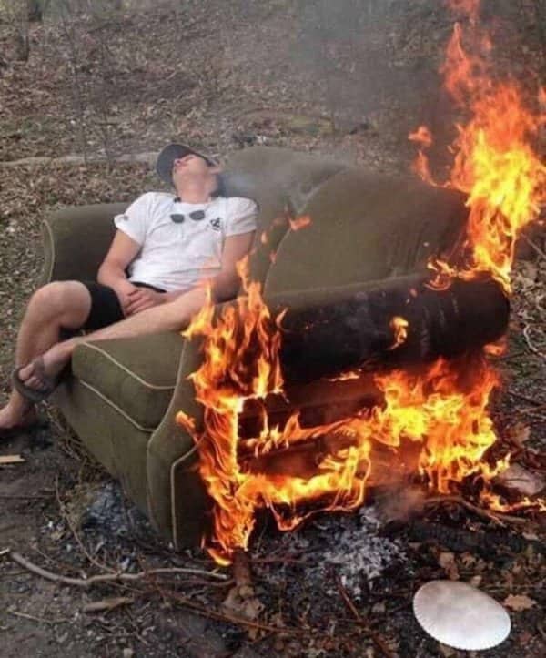 Man napping in an armchair outdoors while the other half of the chair burns