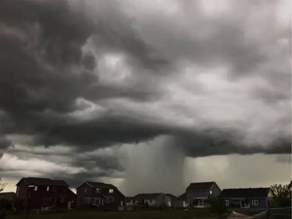 Dark storm cloud dumping a single column of rain over a suburban neighborhood