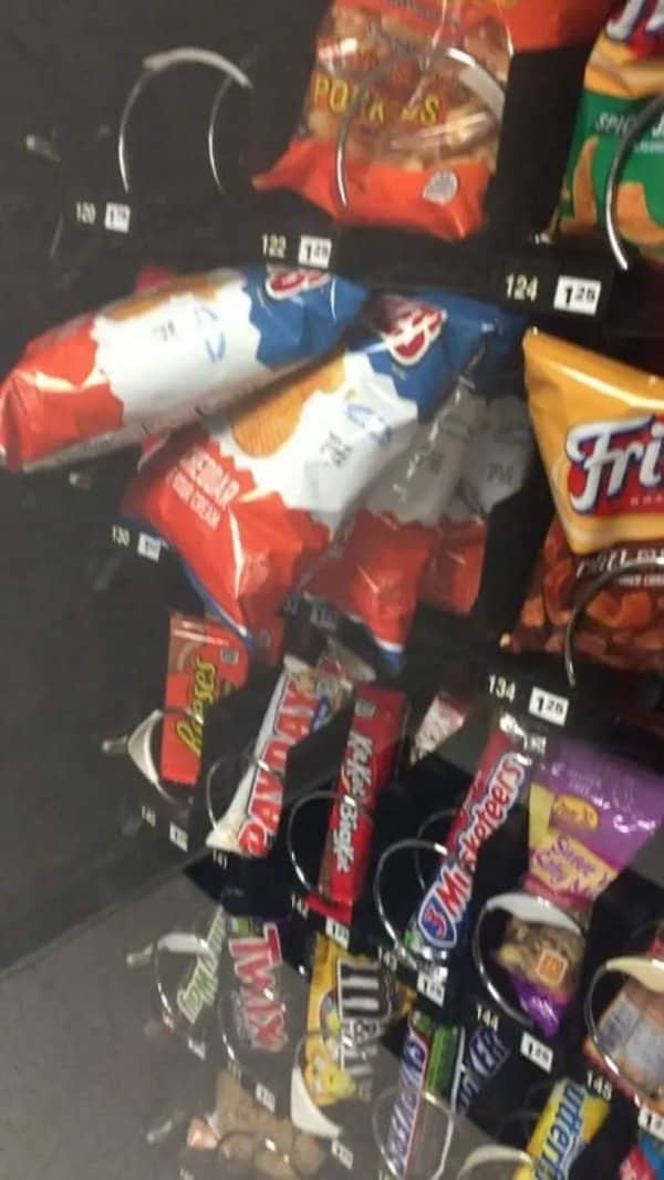 Vending machine with bags of chips and candy tangled and stuck in the coils