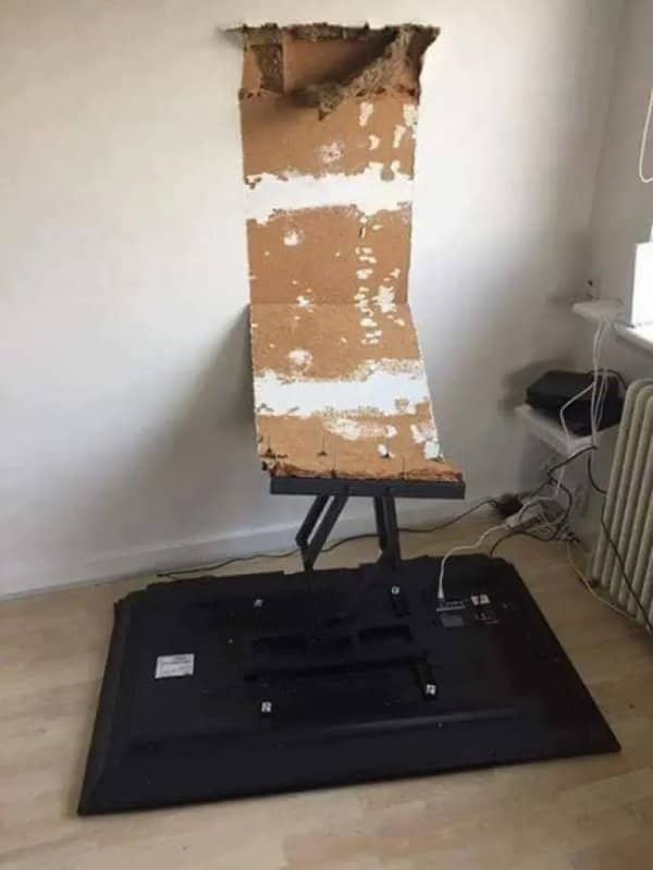 TV lying face down on the floor, its wall mount still attached to a torn chunk of wall