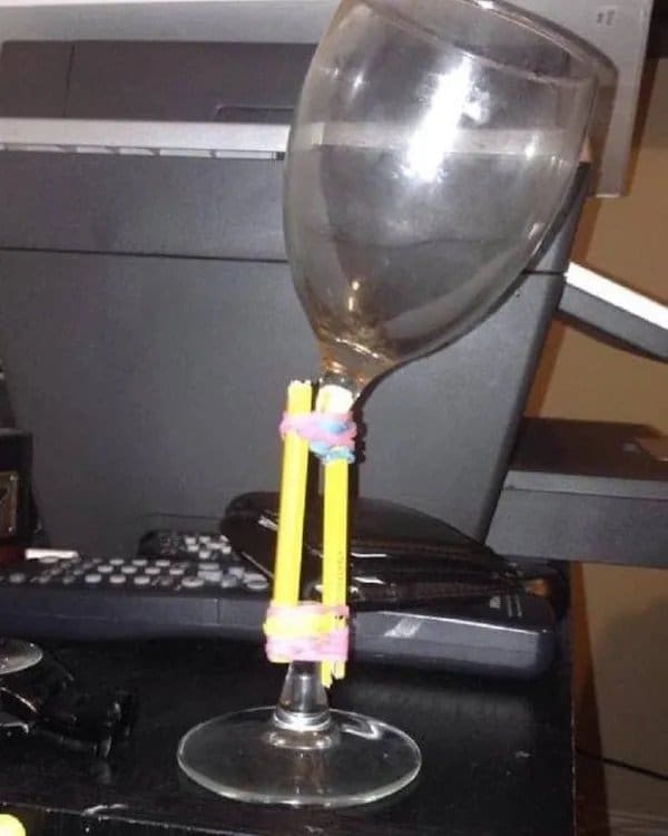Broken wine glass stem splinted back together with two pencils and rubber bands.