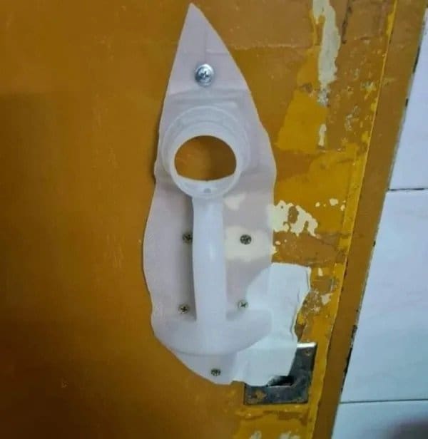 Cut plastic bottle screwed onto a wooden door as a replacement handle.