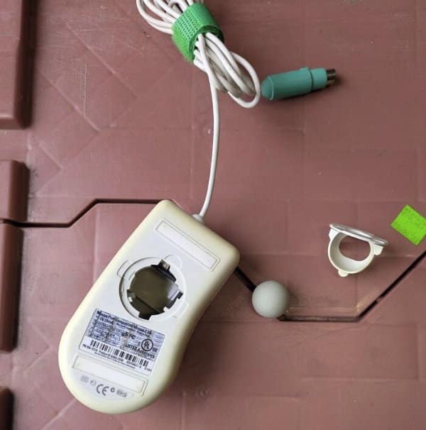 Close-up view of the underside of a vintage computer ball mouse disassembled with its rubber tracking ball removed as retro tech.