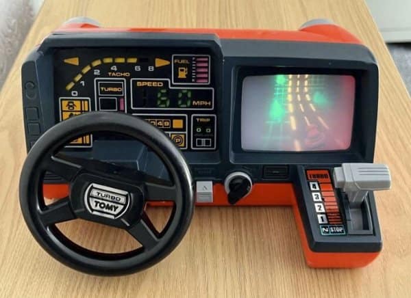 Tomy Turnin' Turbo Dashboard driving simulator toy featuring a steering wheel, gear stick, and illuminated road screen as retro tech.