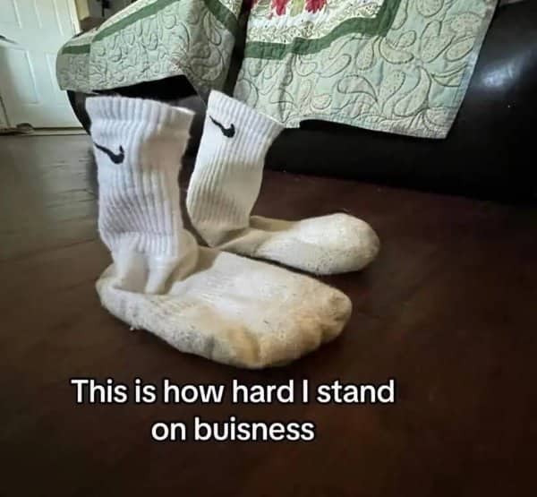 Pair of dirty white Nike socks standing up stiff on their own on a wooden floor