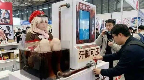 Convention booth with a costumed person's feet soaking in a tank of cola served from a tap
