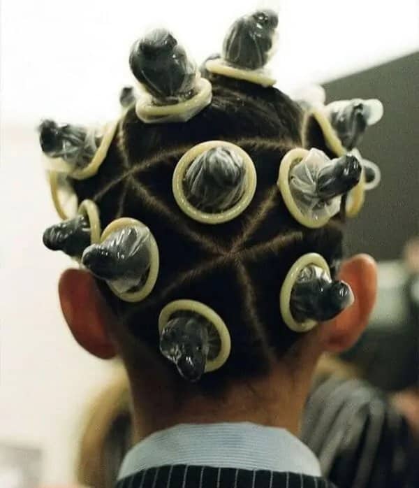 Back of a head with twisted hair knots, each one covered with a stretched latex sheath