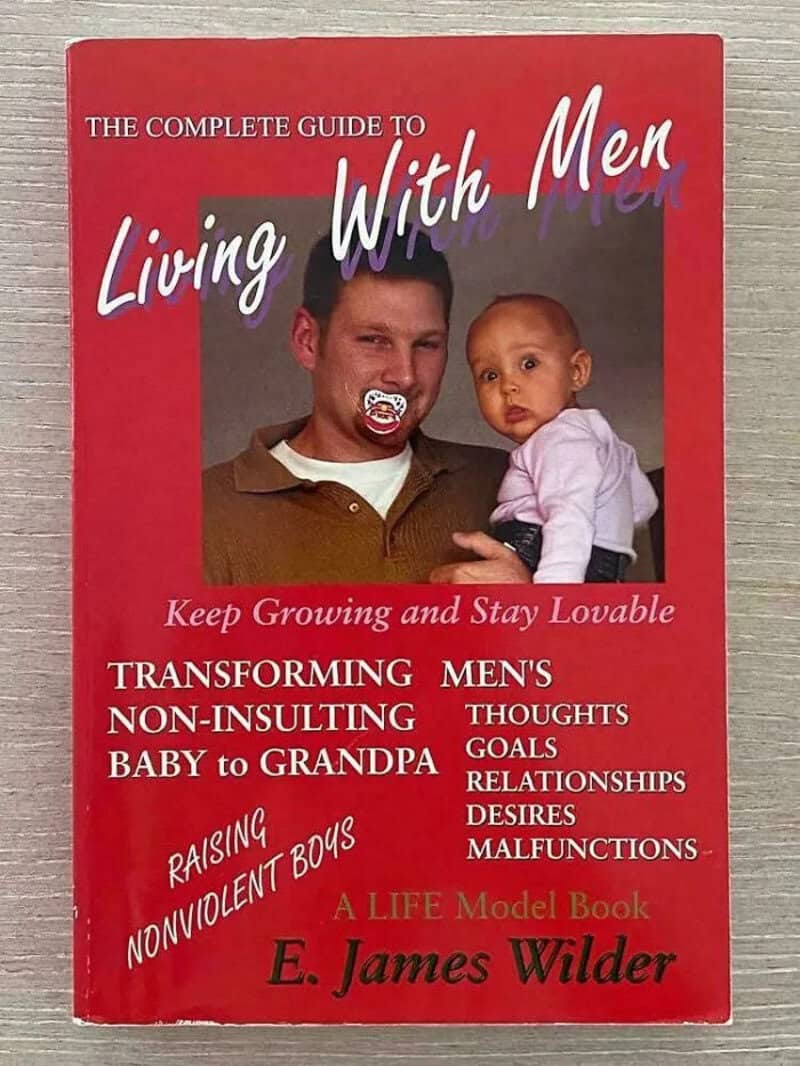 Self-help book The Complete Guide to Living With Men showing a man with a pacifier holding a baby.